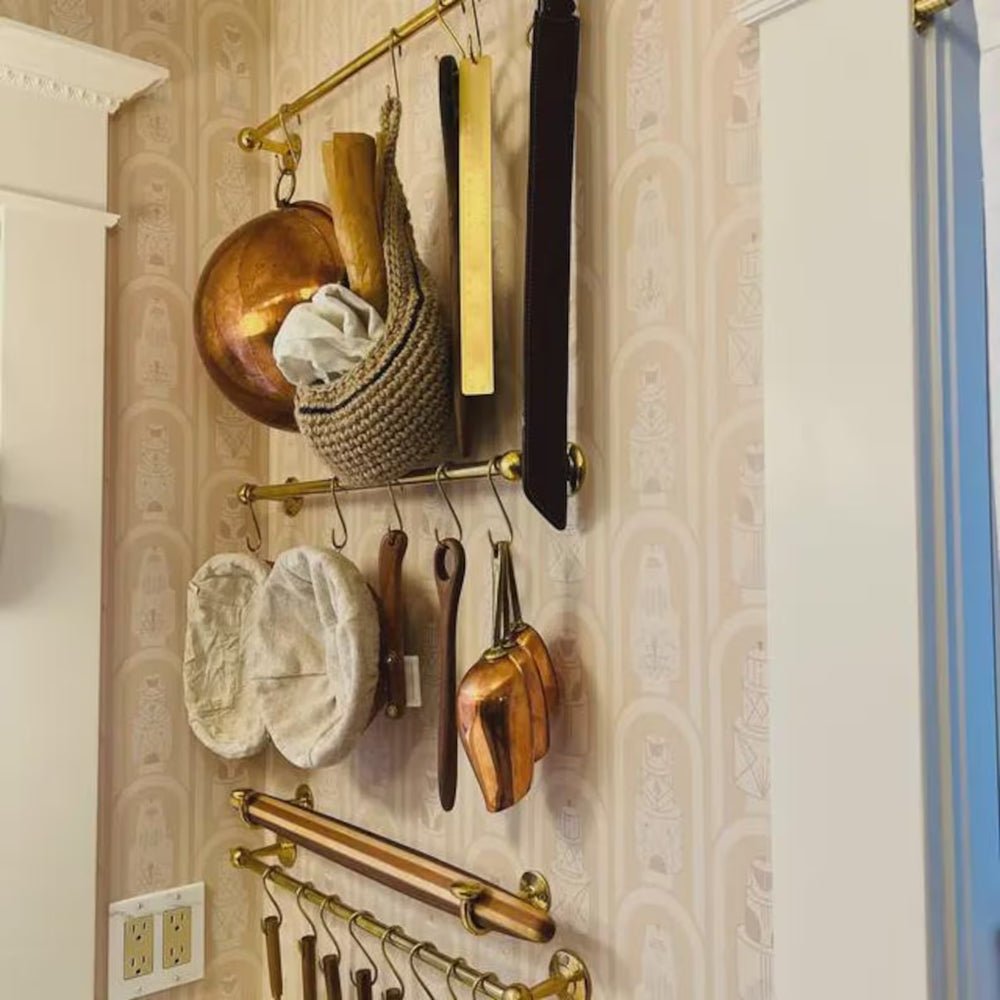 Wall-mounted kitchen utensil holder with various tools on a patterned wall.