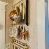 Wall-mounted kitchen utensil holder with various tools on a patterned wall.