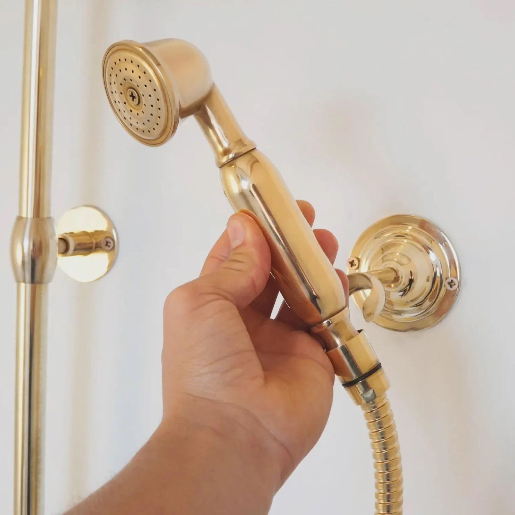 Gold handheld shower head held by a hand 