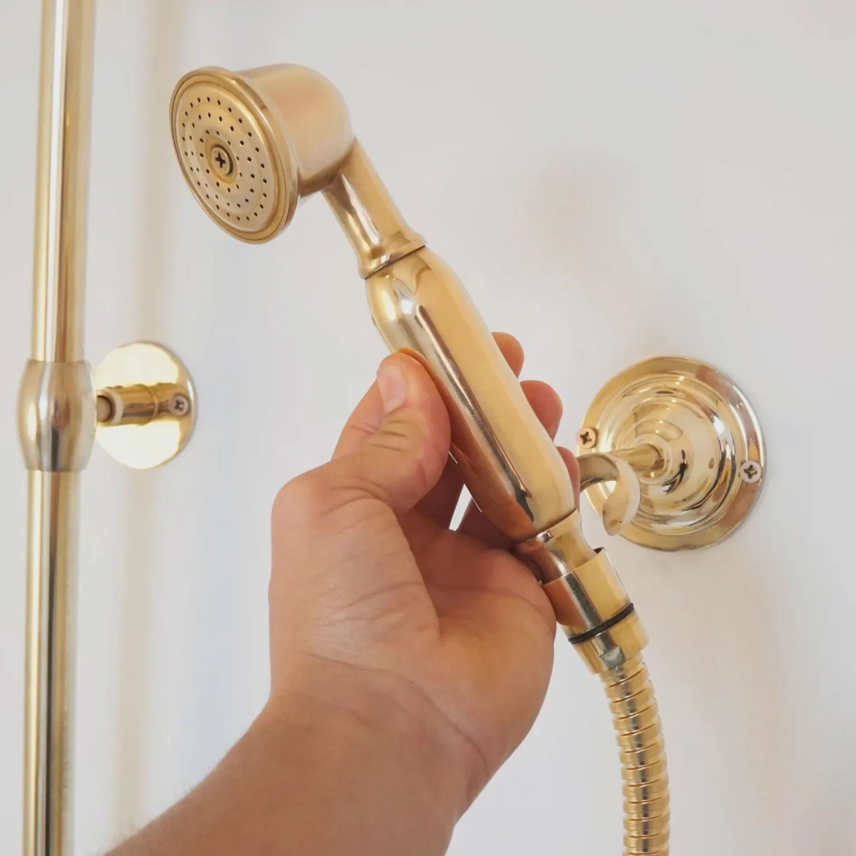 Gold handheld shower head held by a hand 