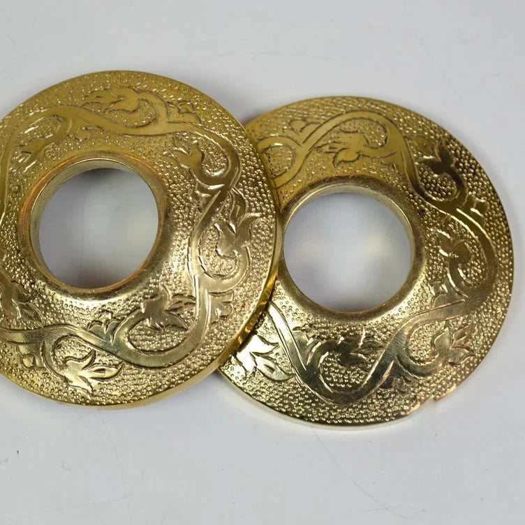 Two gold circular decorative objects with intricate patterns on a white background