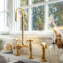 Antique un lacquered brass bridge kitchen faucet with cross handles and a high spout