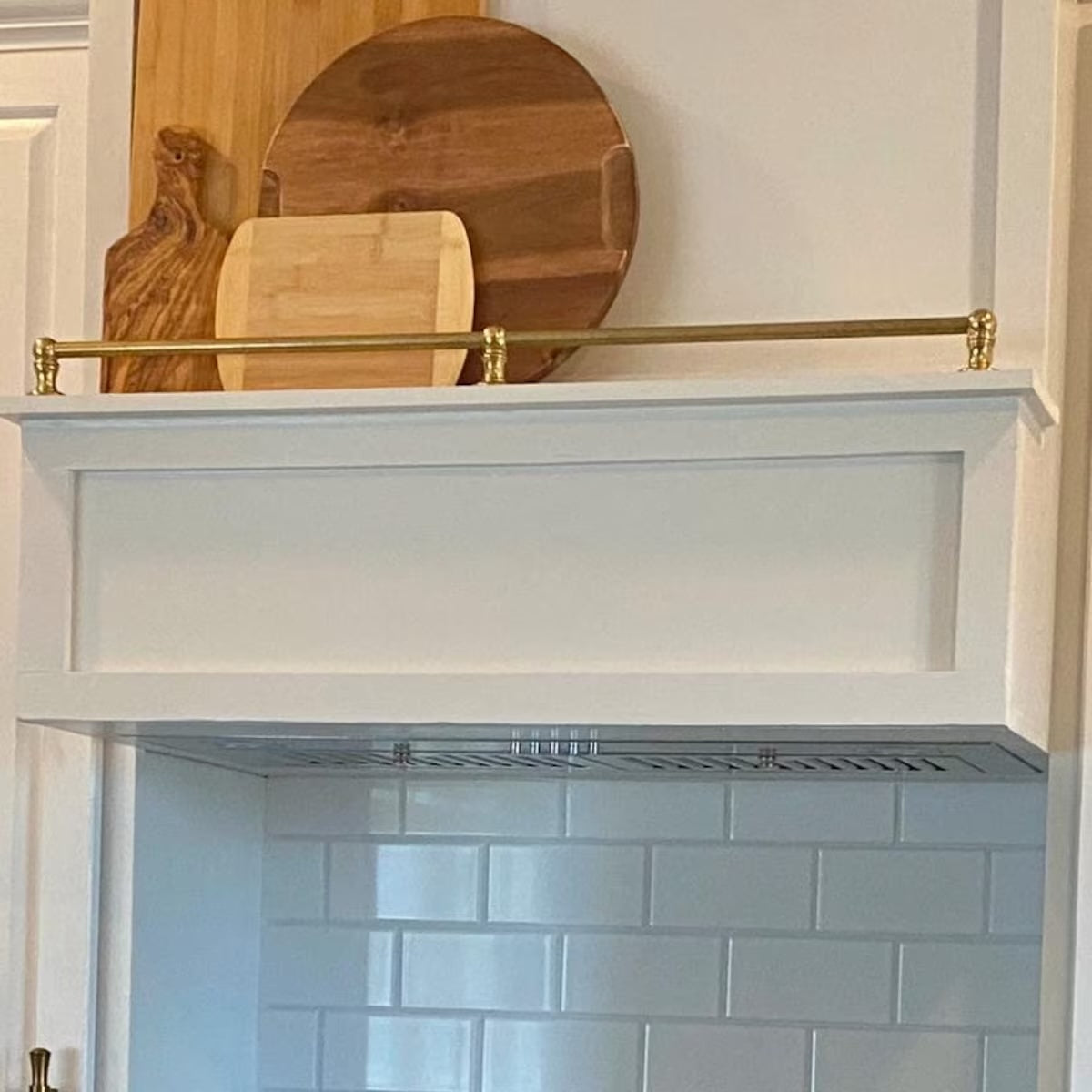 Kitchen shelf with a gold handle against a white tiled wall