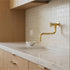 polished brass wall-mounted faucet with a single cross handle.