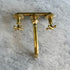 A polished brass three-hole faucet set with a central spout and two cross-handle valves, mounted on a white and gray veined marble surface.