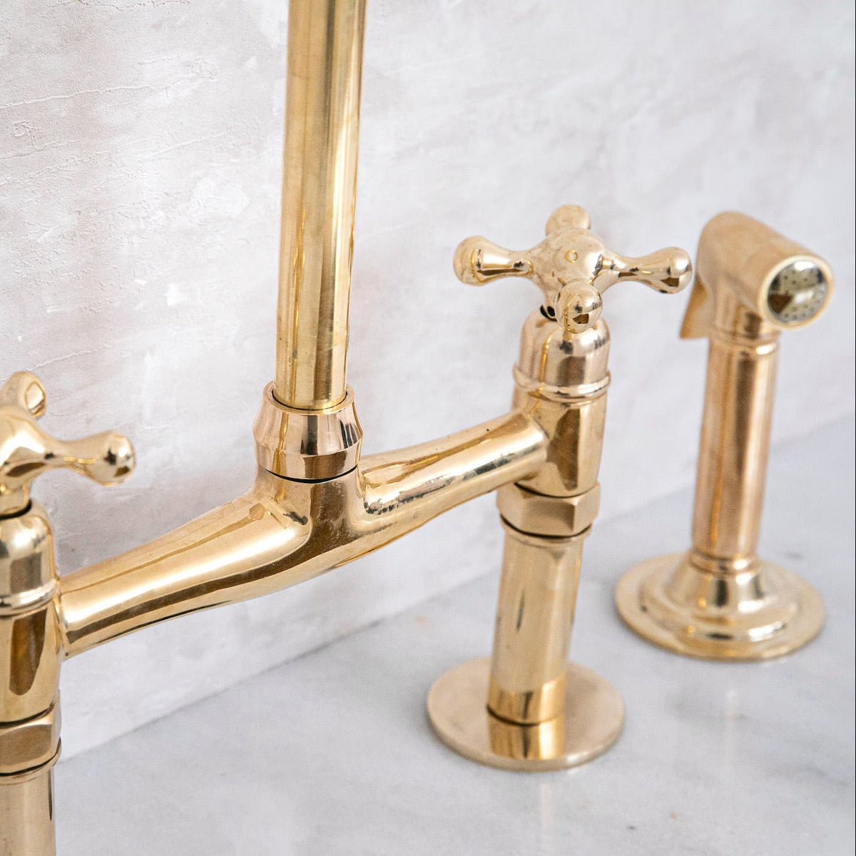Gold kitchen bridge faucet set on a marble surface