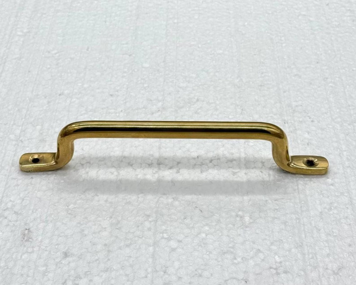 Unlacquered brass cabinet pull handle with a curved bar and two flat mounting bases