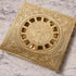 An engraved brass square shower drain with a geometric pattern.