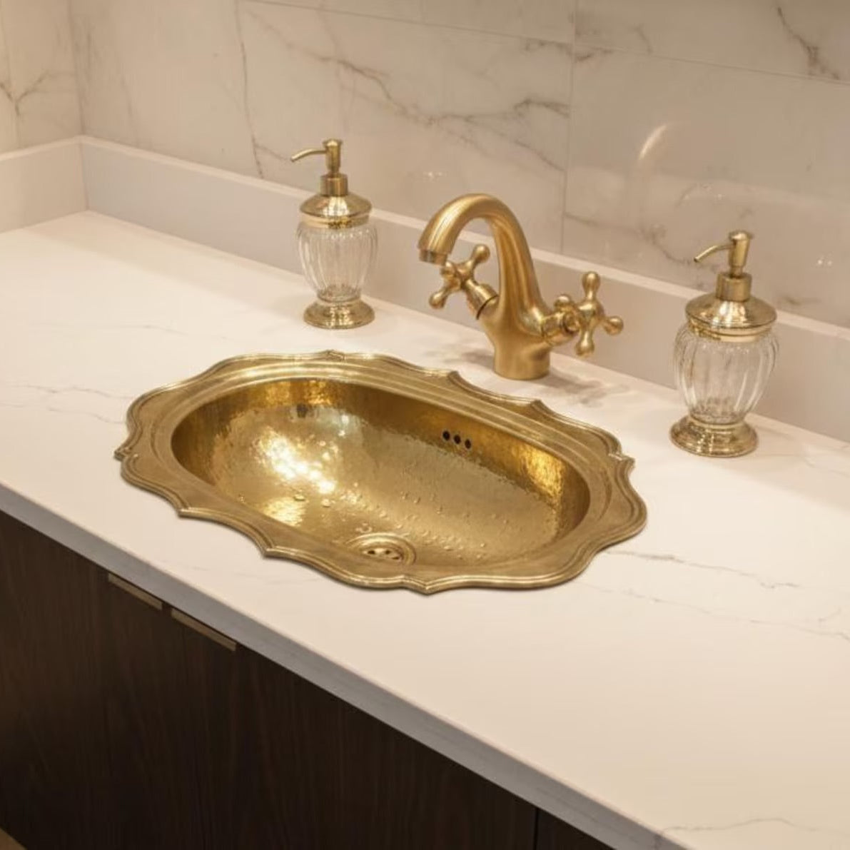 An ornate brass oval sink basin with a matching brass faucet 